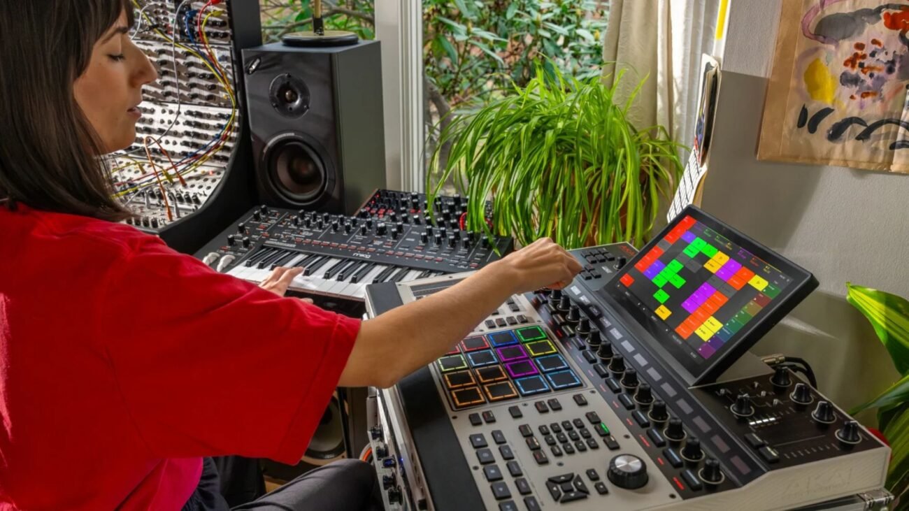 A woman plays an MPC XL and synthesizer in a home studio